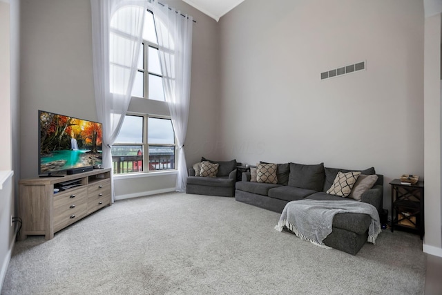 living room with carpet floors, a healthy amount of sunlight, and a high ceiling