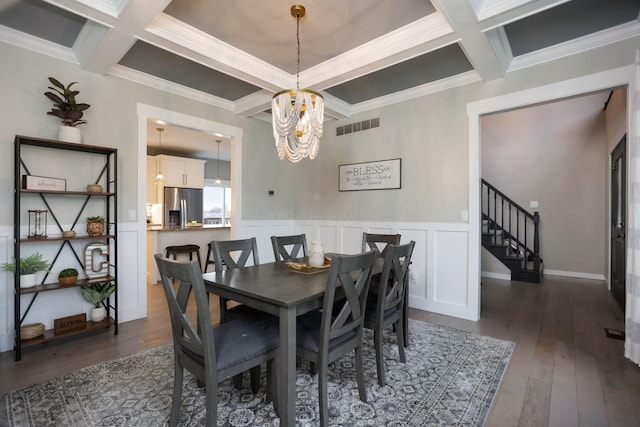 dining area with ornamental molding, dark hardwood / wood-style floors, coffered ceiling, and a notable chandelier