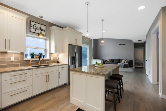 kitchen featuring sink, a kitchen island, hanging light fixtures, and light hardwood / wood-style flooring