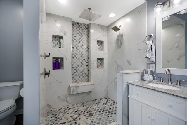 bathroom with a tile shower, vanity, and toilet