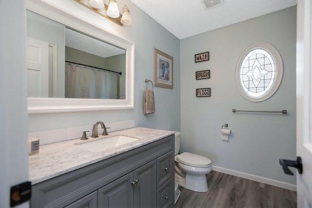 bathroom featuring wood-type flooring, vanity, and toilet