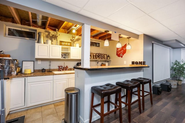 kitchen featuring white cabinets, sink, hanging light fixtures, a kitchen bar, and kitchen peninsula