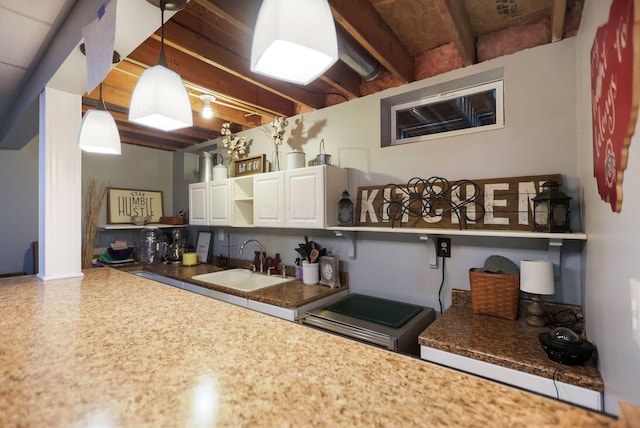 kitchen featuring beamed ceiling, white cabinetry, hanging light fixtures, and sink