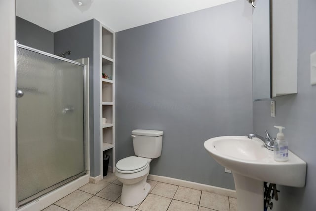 bathroom featuring tile patterned flooring, toilet, and a shower with door