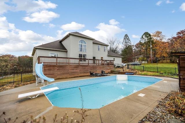 view of swimming pool with a diving board, a deck, and a water slide