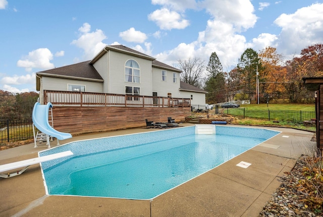 view of pool with a diving board, a wooden deck, and a water slide