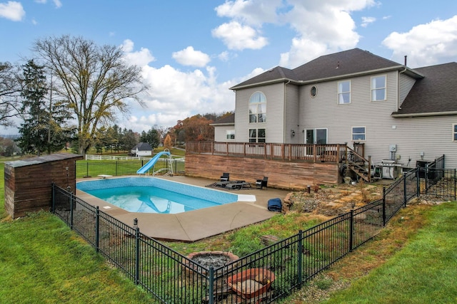 view of pool with a lawn, a wooden deck, and a water slide