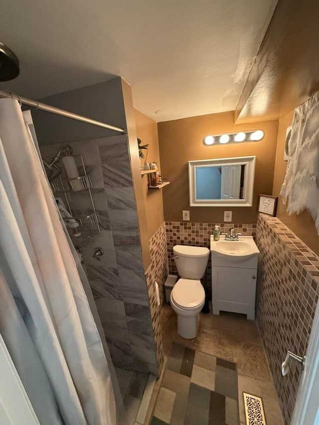 bathroom featuring walk in shower, tile patterned floors, toilet, vanity, and tile walls