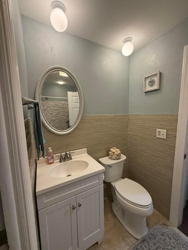 bathroom featuring tile patterned floors, vanity, toilet, and tile walls