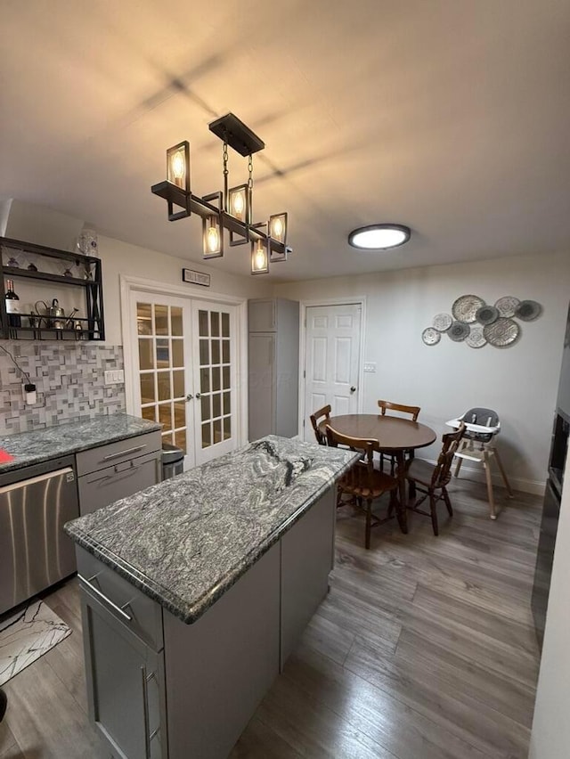 kitchen featuring french doors, dishwasher, a center island, decorative light fixtures, and gray cabinets