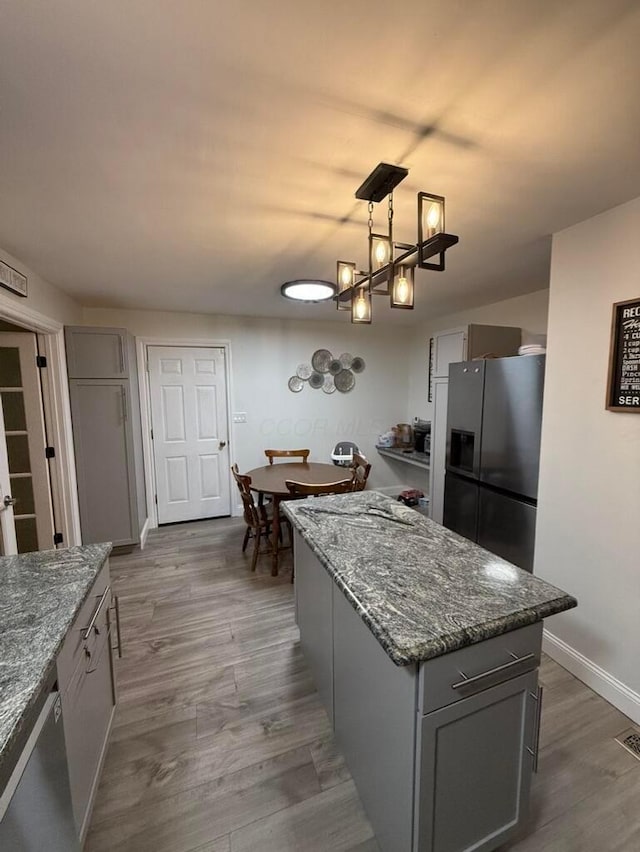 kitchen featuring appliances with stainless steel finishes, gray cabinets, hanging light fixtures, and hardwood / wood-style flooring