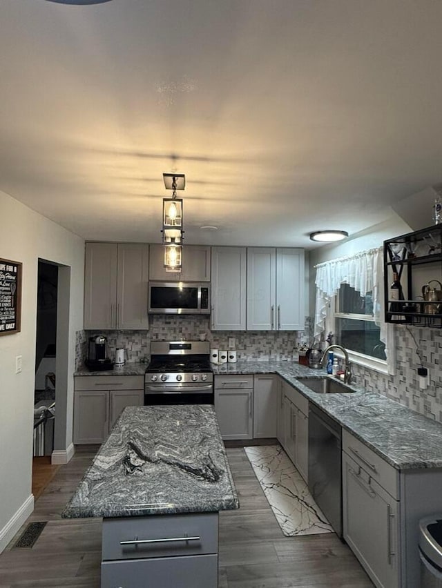 kitchen featuring sink, gray cabinets, decorative light fixtures, a kitchen island, and stainless steel appliances