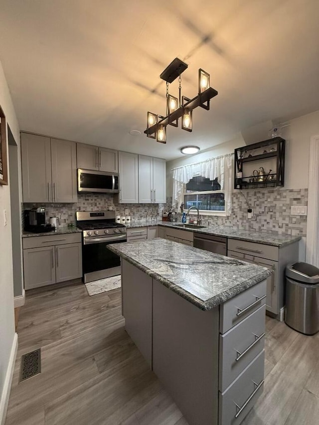 kitchen featuring decorative backsplash, appliances with stainless steel finishes, and gray cabinetry