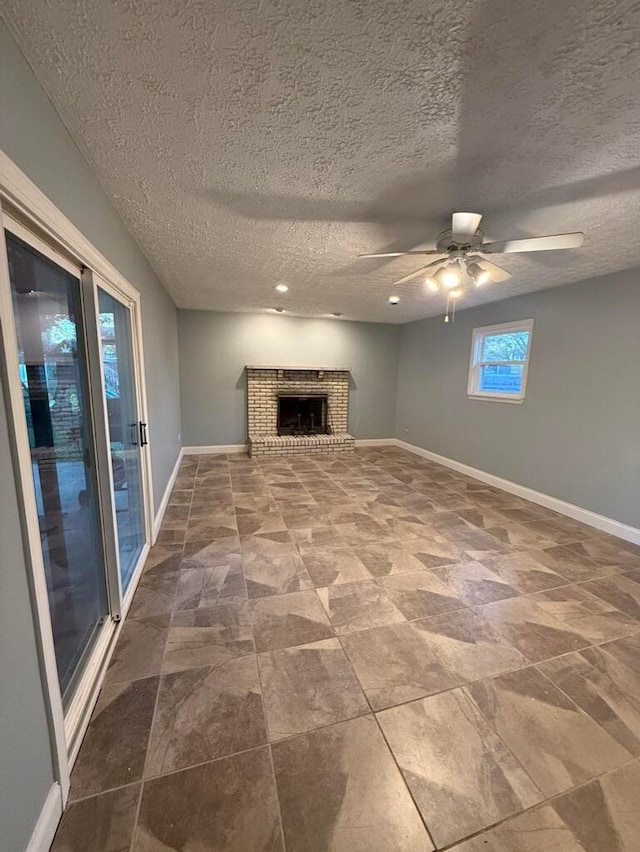 unfurnished living room with a textured ceiling, a brick fireplace, and ceiling fan