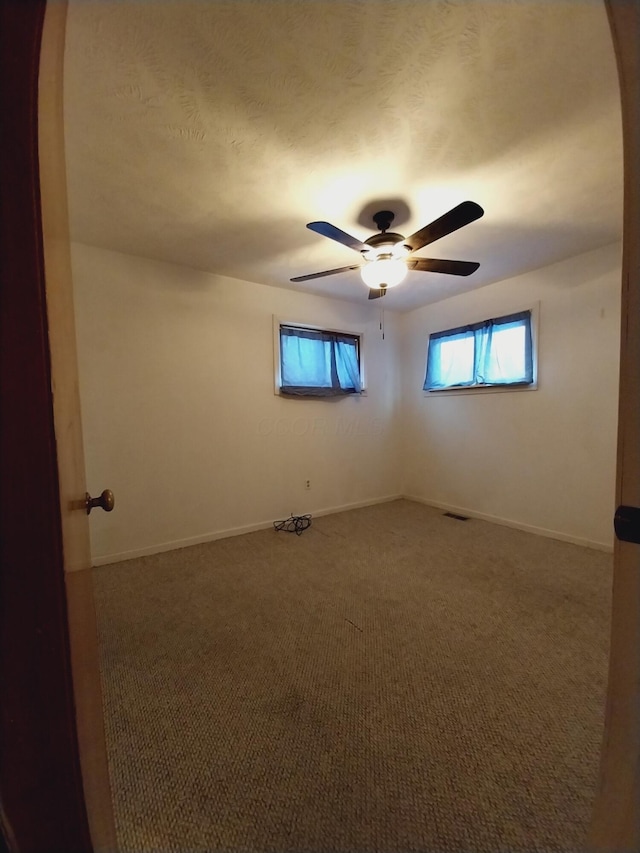 carpeted spare room featuring ceiling fan