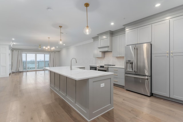 kitchen with hanging light fixtures, light stone counters, crown molding, appliances with stainless steel finishes, and light wood-type flooring