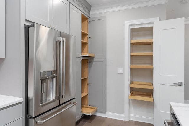 kitchen with high end fridge, light stone countertops, dark wood-type flooring, and ornamental molding