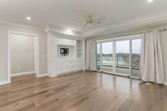 unfurnished living room with ceiling fan, wood-type flooring, ornamental molding, and built in shelves