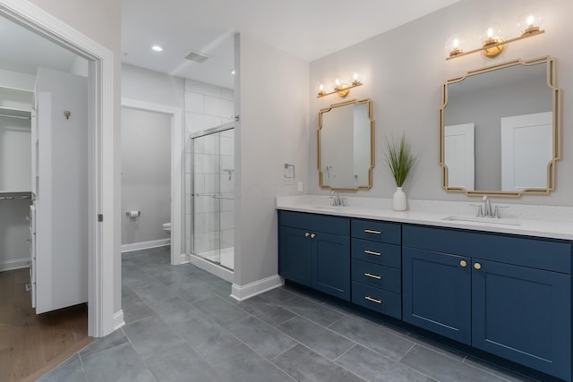 bathroom featuring tile patterned floors, vanity, toilet, and a shower with shower door