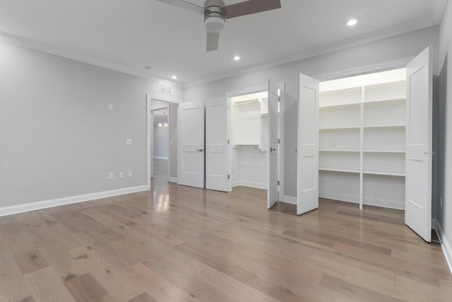 unfurnished bedroom with a spacious closet, ceiling fan, light wood-type flooring, and ornamental molding