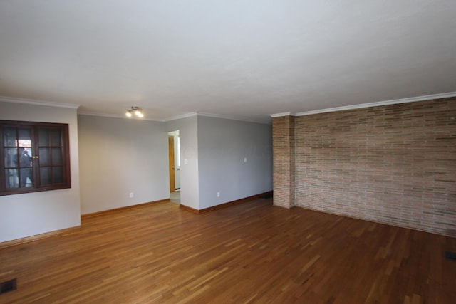 empty room featuring hardwood / wood-style flooring, ornamental molding, and brick wall