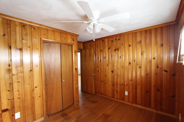 empty room with hardwood / wood-style flooring, ceiling fan, crown molding, and wood walls