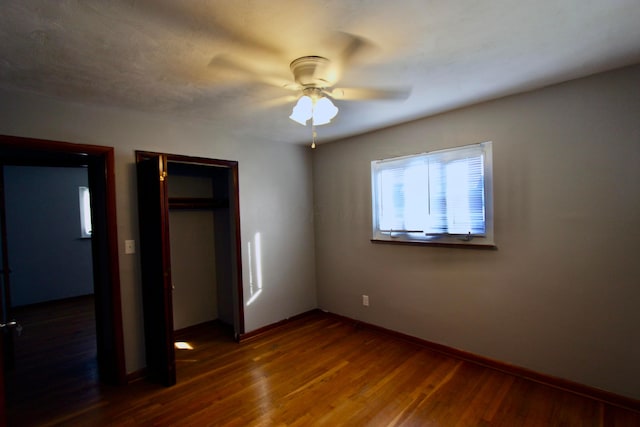 unfurnished bedroom with ceiling fan, dark hardwood / wood-style flooring, and a closet