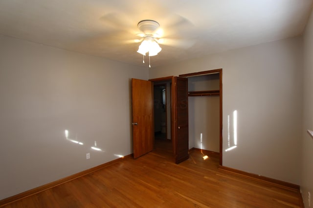 unfurnished bedroom with ceiling fan, a closet, and hardwood / wood-style flooring