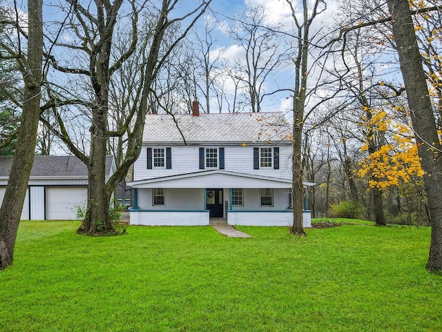 view of front of home with covered porch, an outbuilding, a garage, and a front lawn