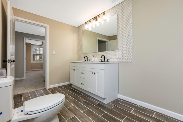 bathroom with vanity, toilet, and tasteful backsplash