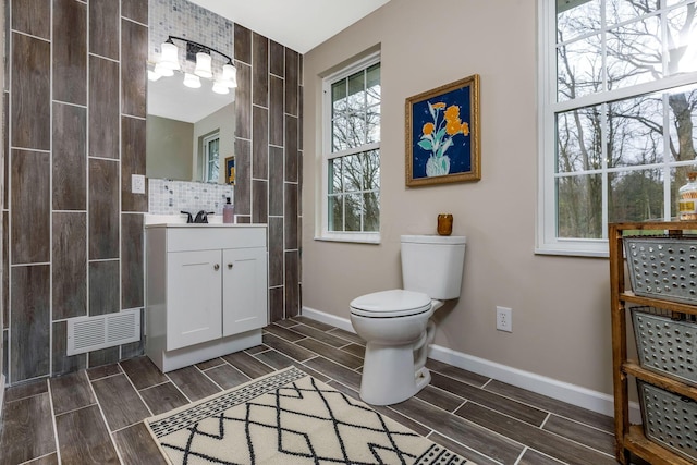 bathroom featuring vanity, toilet, and decorative backsplash