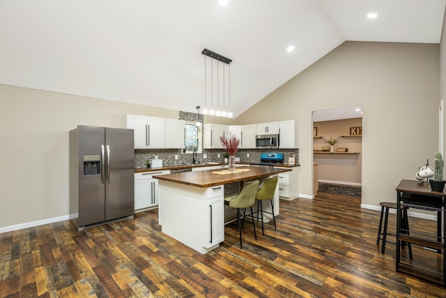 kitchen with white cabinetry, high vaulted ceiling, wooden counters, a kitchen island, and appliances with stainless steel finishes