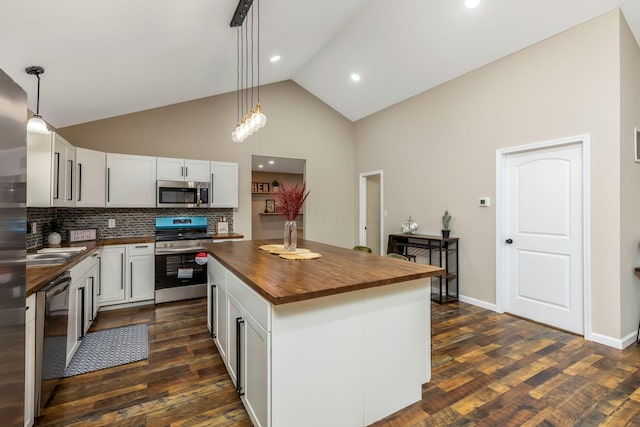 kitchen with wood counters, appliances with stainless steel finishes, decorative light fixtures, high vaulted ceiling, and a kitchen island