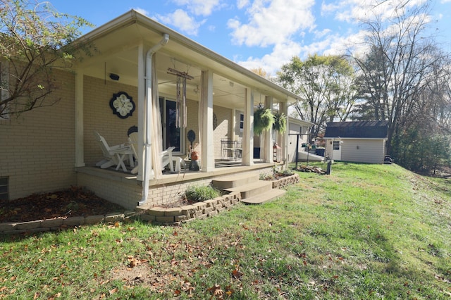 rear view of property with covered porch, a yard, and a storage shed