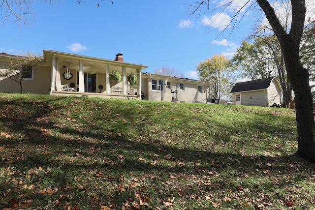 back of property with covered porch and a yard