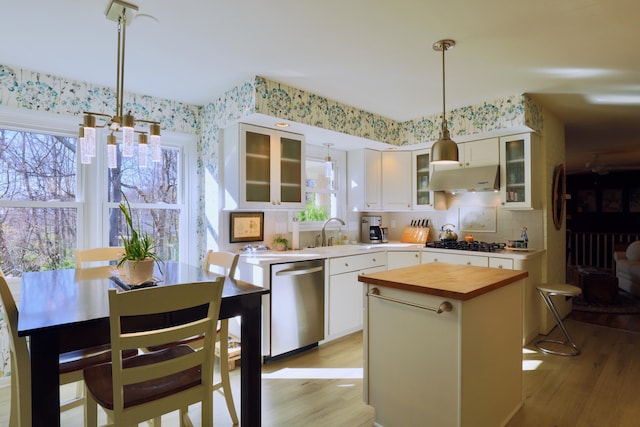 kitchen with stainless steel appliances, decorative light fixtures, white cabinetry, light hardwood / wood-style flooring, and a kitchen island