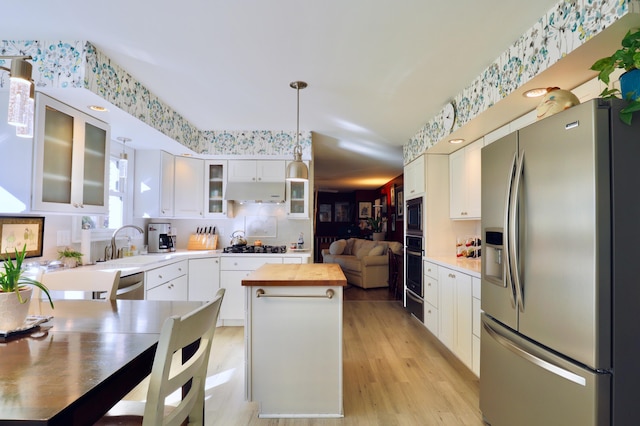 kitchen with white cabinets, appliances with stainless steel finishes, a center island, and pendant lighting