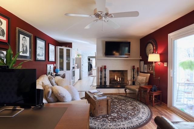 living room featuring ceiling fan, light hardwood / wood-style floors, and a fireplace