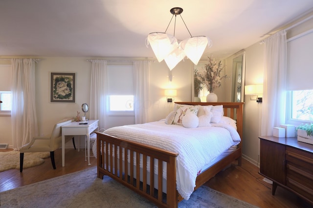 bedroom with hardwood / wood-style floors, an inviting chandelier, and multiple windows