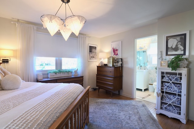 bedroom featuring an inviting chandelier, dark wood-type flooring, and ensuite bath