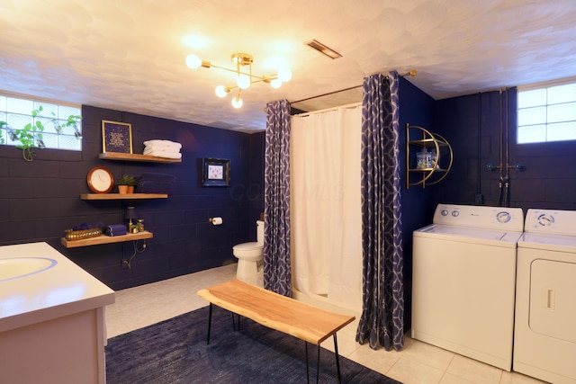 laundry room with washing machine and dryer, light tile patterned flooring, and a notable chandelier