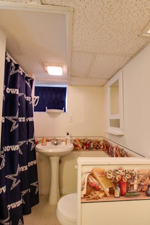 bathroom with toilet, a drop ceiling, and curtained shower