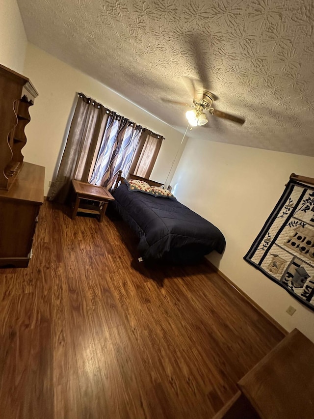 bedroom with ceiling fan, dark wood-type flooring, and a textured ceiling