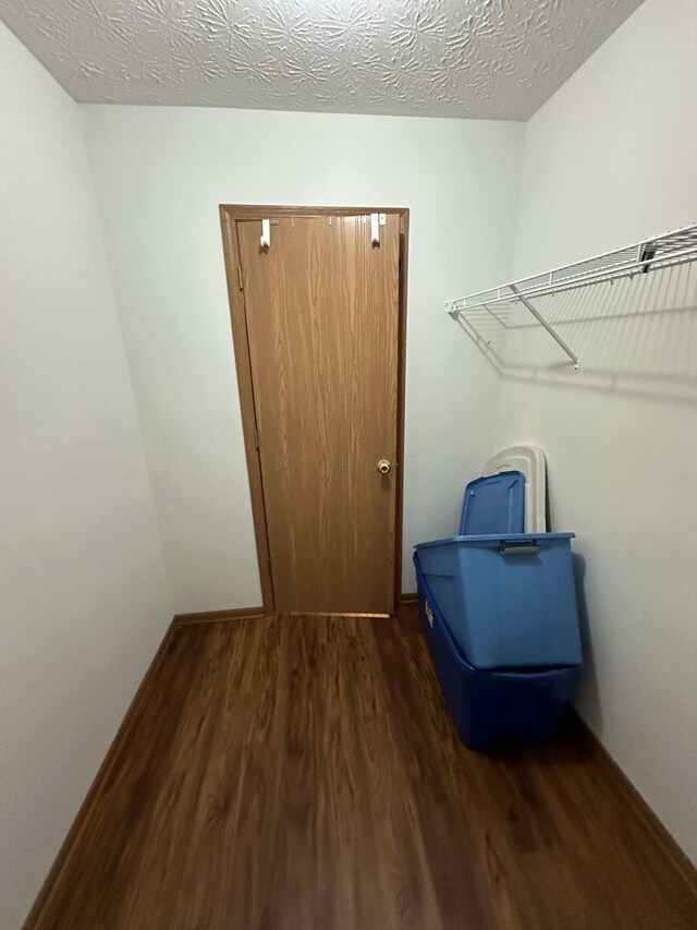 laundry area featuring a textured ceiling and dark hardwood / wood-style flooring