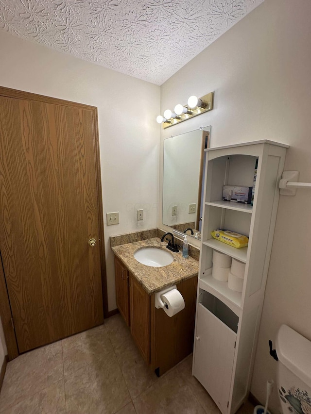 bathroom with vanity, tile patterned floors, a textured ceiling, and toilet