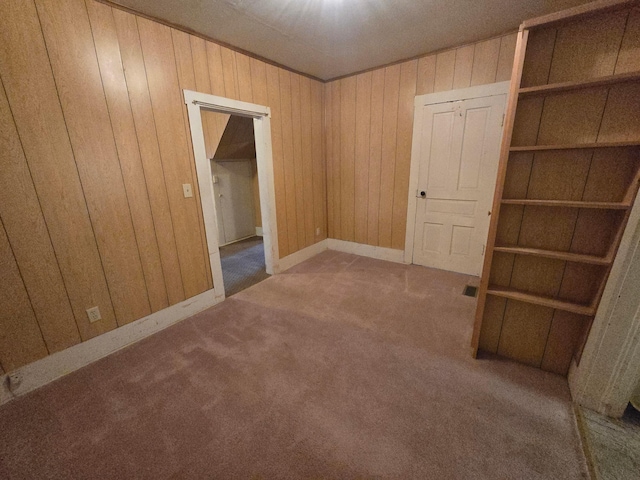 carpeted empty room featuring wood walls