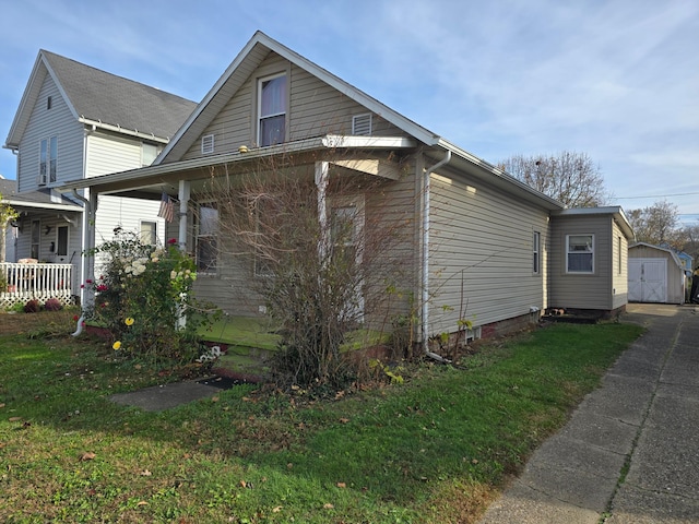 view of home's exterior with a yard, an outbuilding, and a porch