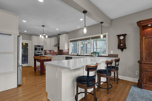 kitchen featuring a breakfast bar, white cabinets, backsplash, and kitchen peninsula