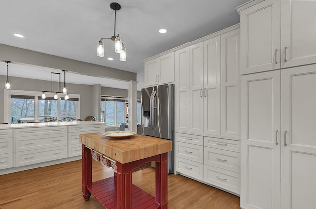 kitchen with pendant lighting, stainless steel fridge with ice dispenser, light hardwood / wood-style flooring, and white cabinets