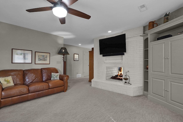 living room featuring ceiling fan, a fireplace, and light carpet